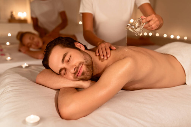 Los cónyuges que se relajan durante el masaje de parejas con aceite en el spa - Foto, imagen