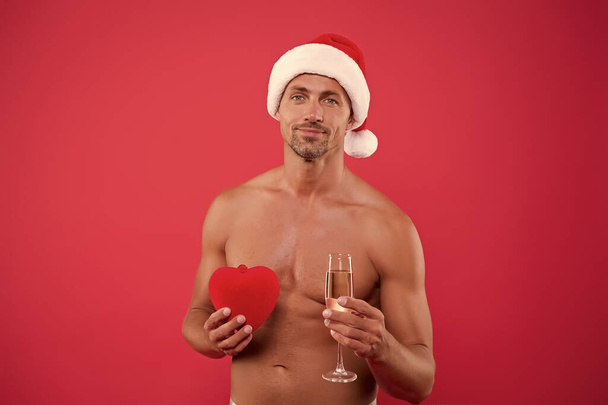 Sexy Santa. Attractive man nude muscular torso Santa hat. Sparkling wine and gift. Romantic evening. Party for adults. Handsome Santa in love. Greetings concept. Happy new year and merry christmas - Photo, image