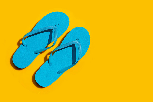 Blaue Flip Flops auf gelbem Hintergrund. Sommerferienkonzept genießen. - Foto, Bild