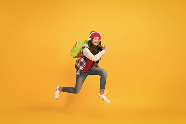 Time to chill. small schoolgirl running to school. hurry up its holiday time. child being late. sense of freedom. childhood activity. girl listen music in headphones with backpack. back to school - Zdjęcie, obraz