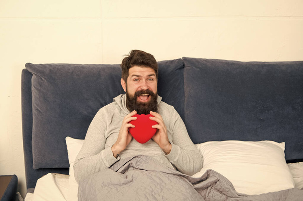 Love and relations. Valentines day. Surprise gift. Holiday celebration. Happy morning. Bearded hipster need some love. Lack of love. Man relaxing in bed. Looking for partner. Take care of heart - Photo, image