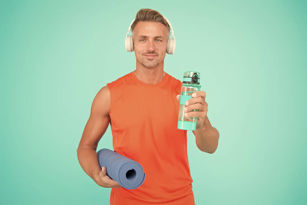 Music for workout. Yoga is my hobby. Personal training. Challenge multiple muscle groups. Man practicing yoga at home. Mature sportsman with yoga mat. Workouts with modifications for different levels - Valokuva, kuva