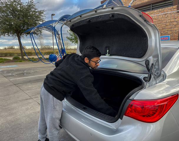 Vista de perto de um homem limpando o porta-malas de seu carro no estacionamento a vácuo self serve - Foto, Imagem