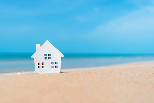 Gesloten kleine huis modellen op zand met zonlicht en strand achtergrond. - Foto, afbeelding