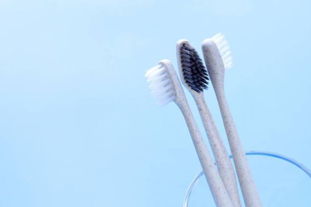 Tandenborstels in een glas op wit. Kopieerruimte - Foto, afbeelding