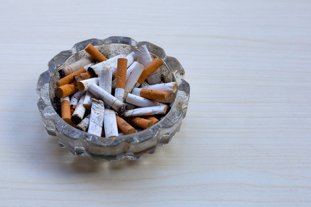 Cigarettes buds in a transparent ashtray on table - Photo, Image