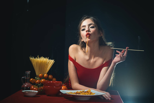 Young sexy woman eating tasty pasta on black. - Foto, Bild