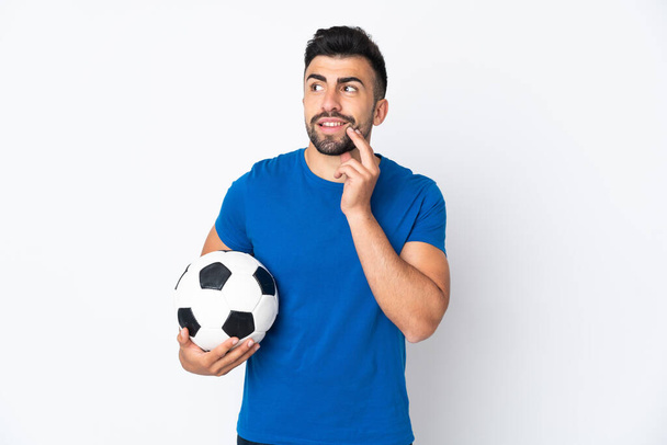 Fešák mladý fotbalista muž přes izolovanou zeď myšlení nápad, zatímco vzhlíží - Fotografie, Obrázek