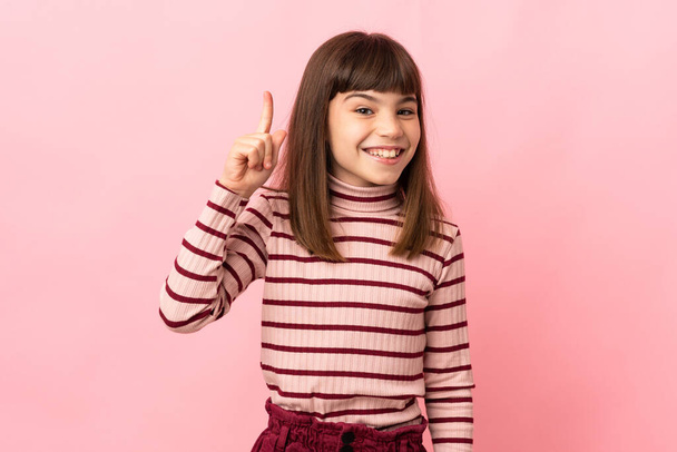 Pieni tyttö eristetty vaaleanpunainen tausta aikoo toteuttaa ratkaisun nostaessaan sormea ylös - Valokuva, kuva
