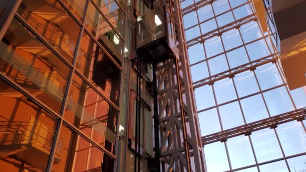 現代のエレベーターは日没の黄金の時間の太陽の下で企業ビルに上下に移動します - 映像、動画