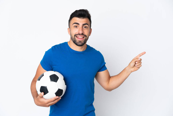 Beau jeune joueur de football homme sur mur isolé pointant doigt sur le côté - Photo, image