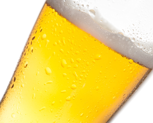 detalle de vaso inclinado de cerveza fresca con gotas sobre fondo blanco
 - Foto, imagen