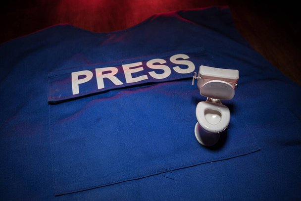 Media Journalistiek nep nieuws concept. Blauwe journalist (pers) vest in het donker met achtergrondverlichting en mist. Toilet op journalistenvest. Selectieve focus - Foto, afbeelding