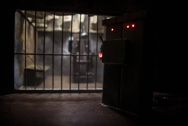 Kivégzési koncepció. Halálbüntetés elektromos szék miniatűr szelektív fókusz belül régi börtönben. Régi börtönrácsok zárja. Kreatív műalkotás dekoráció. Elektromos szék skála modell a sötétben - Fotó, kép
