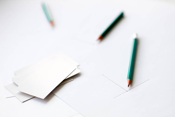comenzar a dibujar en una hoja de papel blanco y tarjetas de visita en blanco. lápices fuera de foco - Foto, Imagen