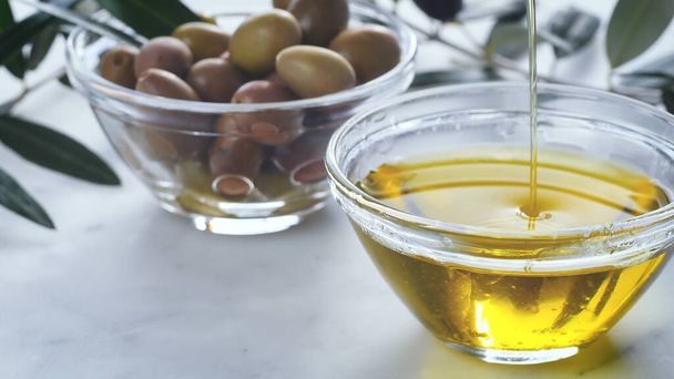 A closeup shot of extra virgin oil falls in a glass bowl, genuine Italian ingredients, - Фото, изображение