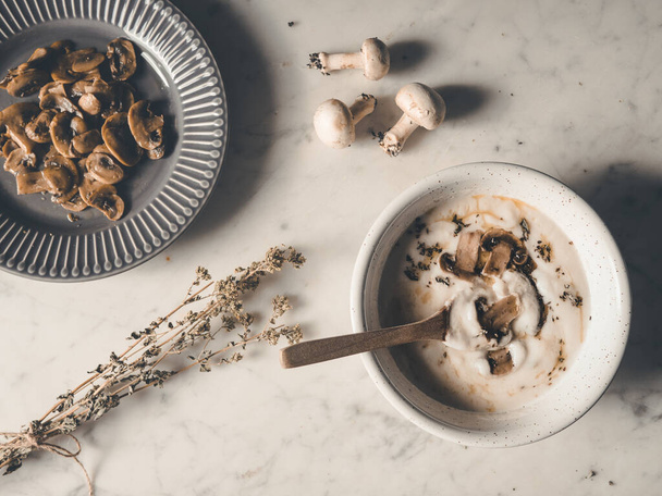 Een bovenaanzicht van witte soep, romig en rustiek met champignons op tafel - Foto, afbeelding