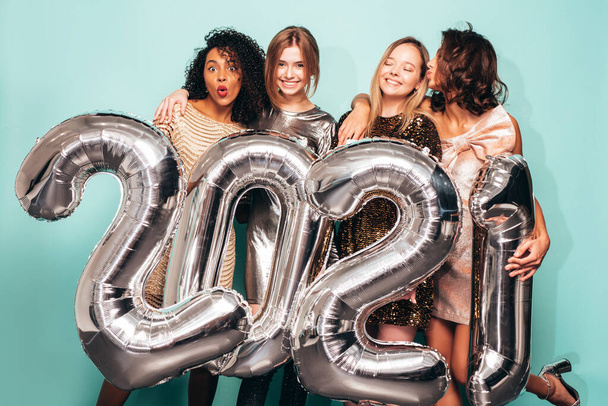Beautiful Women Celebrating New Year.Happy Gorgeous Female In Stylish Sexy Party Dresses Holding Silver 2021 Balloons, Having Fun At New Year's Eve Party. Holiday Celebration.Charming Models  - Valokuva, kuva