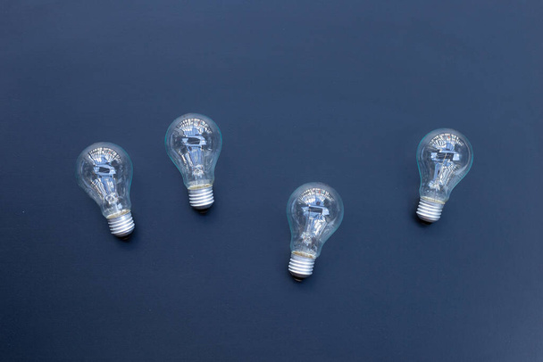 Light bulbs on dark background. Ideas and creative thinking concept. Top view - Fotó, kép