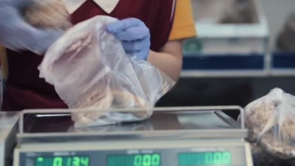 Een werknemer in uniform, met rubberen handschoenen, verpakt peperkoek in een plastic zak voor eenmalig gebruik. Handen van dichtbij. - Video