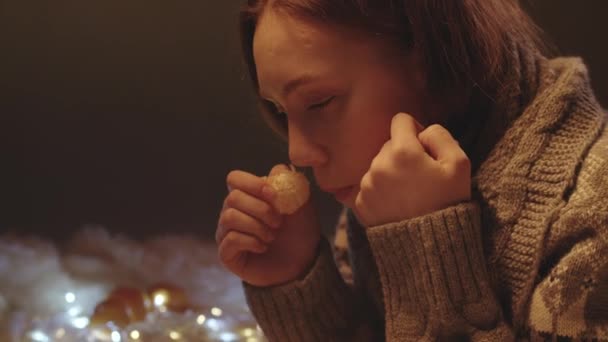 Πλάνα τρώγοντας tangerine κορίτσι σε πλεκτό πουλόβερ - Πλάνα, βίντεο