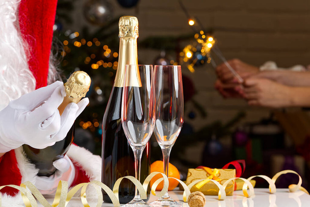 Mann im Weihnachtsmann-Kostüm öffnet eine Flasche Champagner - Foto, Bild