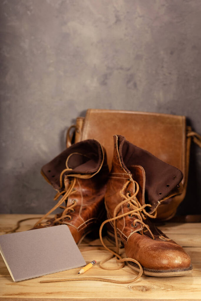 travel vintage old boots shoes at wooden desk table near concrete wall background texture surface - Photo, Image