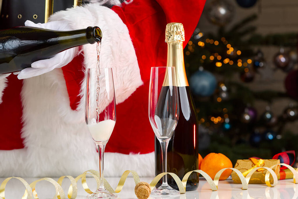Santa claus dress adult pouring out champagne. pouring sparkling wine by glasses, celebration, start of the holiday, success concept - Photo, Image