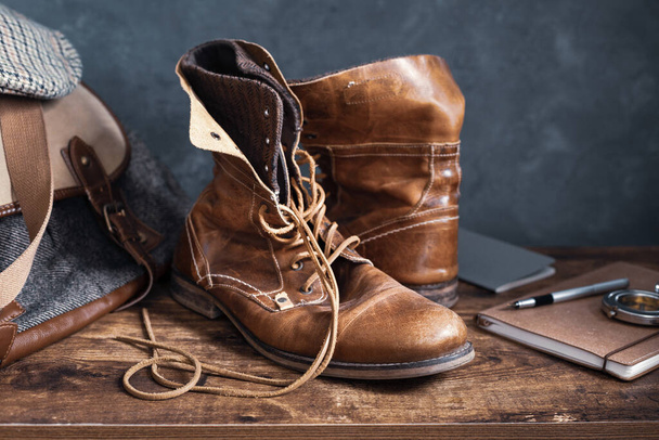 old leather travel vintage boots shoes and bag at wooden table, with wall background texture - Fotoğraf, Görsel