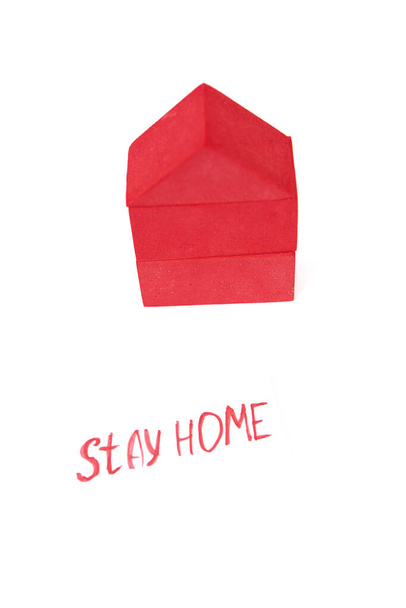 Speelgoedhuis op een witte achtergrond. Een speelgoedhuis gemaakt van rode blokjes. Met een rood bord dat zegt thuis te blijven. Met ruimte om te schrijven - Foto, afbeelding
