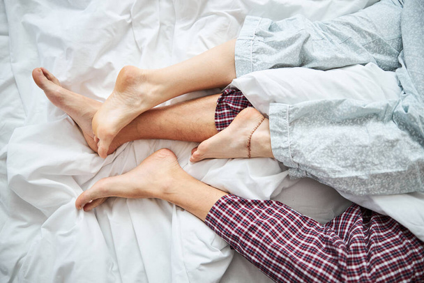 Loving couple with intertwined legs resting in bed - Фото, изображение