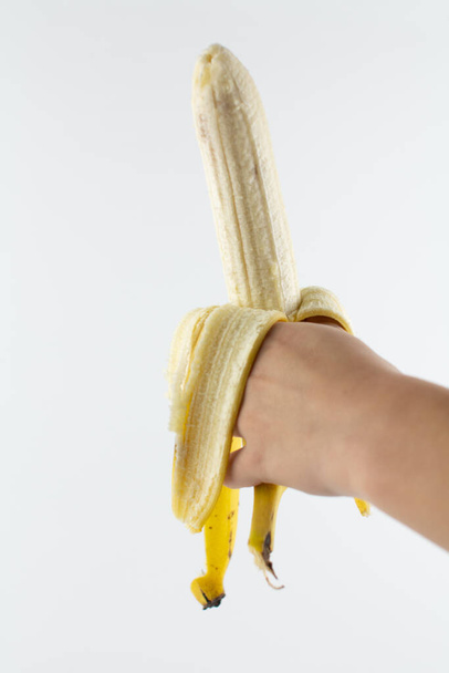 a ripe peeled banana in hand on white background - Foto, Bild