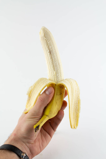 a ripe peeled banana in hand on white background - Foto, imagen