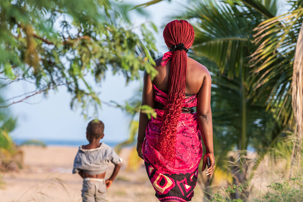 Femme africaine portant des vêtements traditionnels descend à la plage à Keta Ghana Afrique de l'Ouest - Photo, image