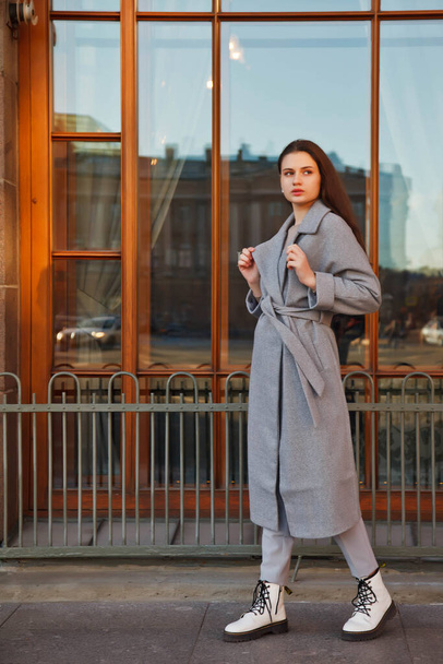 Fashionable young beautiful stylish woman in gray coat walking on street. Autumn fashion trend for smiling, happy, purposeful female. Concept style, fashion, beauty and achievement goals. Copy space - Φωτογραφία, εικόνα