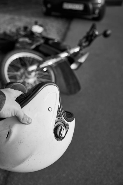 Фото автомобіля, шолом в руках чоловіка і мотоцикл на дорозі, концепція дорожньо-транспортних пригод, чорно-біле фото
. - Фото, зображення