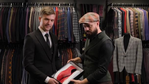 男性の顧客に靴箱を与える販売人。洋服屋のサラリーマンに靴をプレゼントするデザイナー - 映像、動画