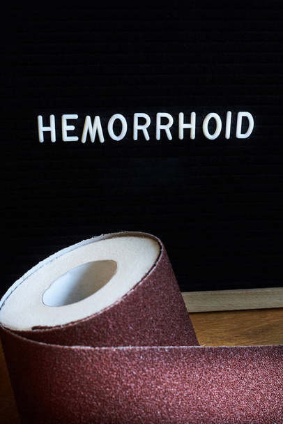 Words Hemorrhoids and a roll of toilet paper wrapped in sandpaper, health problems. - Photo, Image