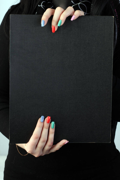 poster in the hands of the girl with painted colored nails - Fotoğraf, Görsel