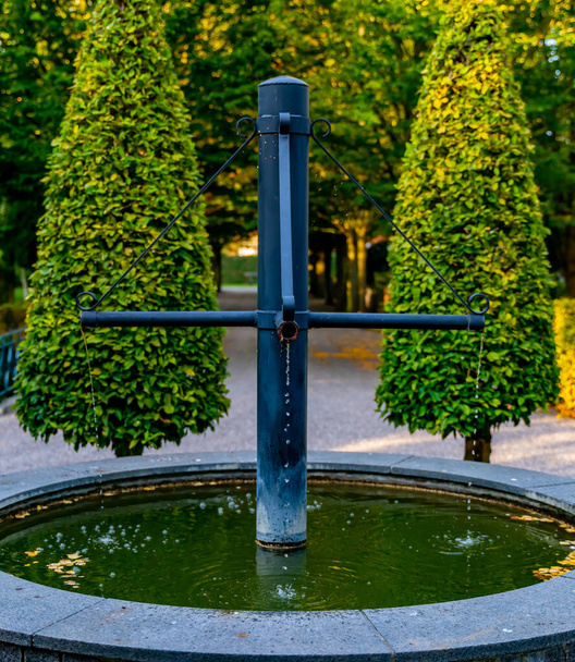 Fuente decorativa y bien hecha de tubos de hierro fundido. En un parque. .. Foto de alta calidad - Foto, Imagen