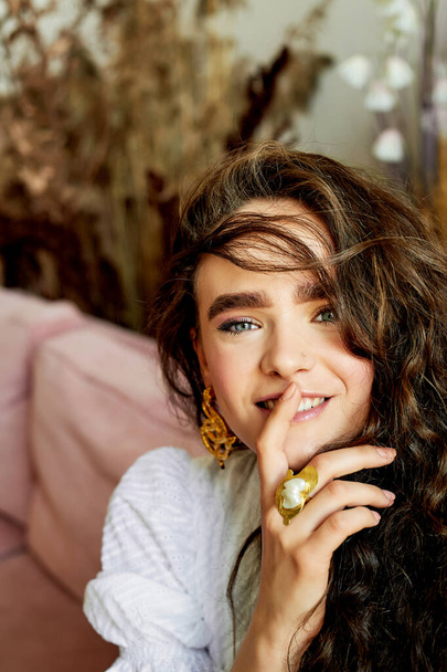 Model with beautiful eyes, curly hair and thick eyebrows. Smiles, finger near lips. Fashion and style - Foto, Imagem