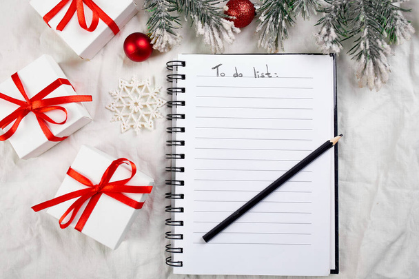 Top kilátás üres notebook csinálni lista és karácsonyi dekoráció, ajándékok fehér textil vászon asztalterítő háttér, lapos laikus, másolás tér, új normál évben. - Fotó, kép