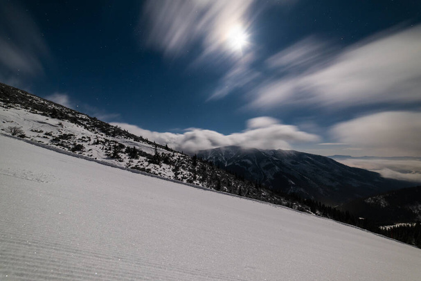 Neige fraîche damée sur la piste de ski à la station de ski par nuit nuageuse. Pistes de dameuse à neige sur une piste de ski de montagne. - Photo, image