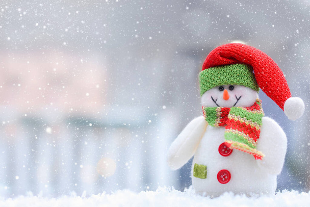 雪の冬の背景に赤い帽子とスカーフのクリスマスの雪だるまテキストのためのスペースをコピー - 写真・画像