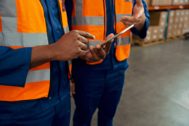 Mid section of two male employees holding digital tablet in manufacturing industry - Foto, Bild