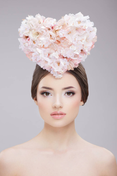 Retrato de belleza frontal. Hermosa chica con flores de primavera y hombros desnudos. Maquillaje creativo y estilo de pelo. - Foto, Imagen