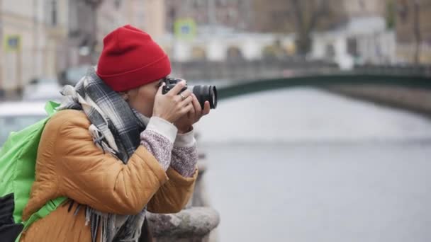 Young middle eastern woman traveler taking pictures while standing near the river on a cool fall day. - Footage, Video