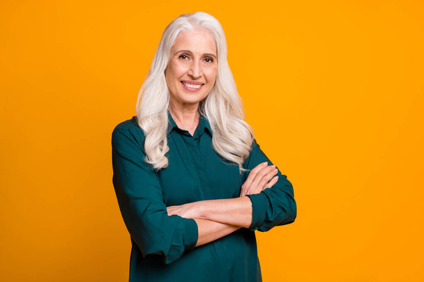 Photo of pretty confident white haired grandma lady holding hands crossed responsible chief company ceo founder wear green shirt isolated bright yellow color background - Fotó, kép