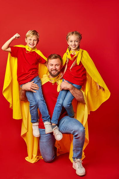 brave and strong father hold superheroes children on shoulders - Φωτογραφία, εικόνα