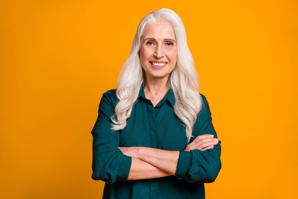 Photo of pretty cheerful white haired grandma lady holding hands crossed responsible chief company ceo founder wear green shirt isolated bright yellow color background - Photo, image